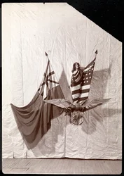 Ein lebendes Bild: ein Modell, das in die amerikanische Flagge gehüllt ist und auf einer Skulptur eines Weißkopfseeadlers steht, 1900 oder 1901
